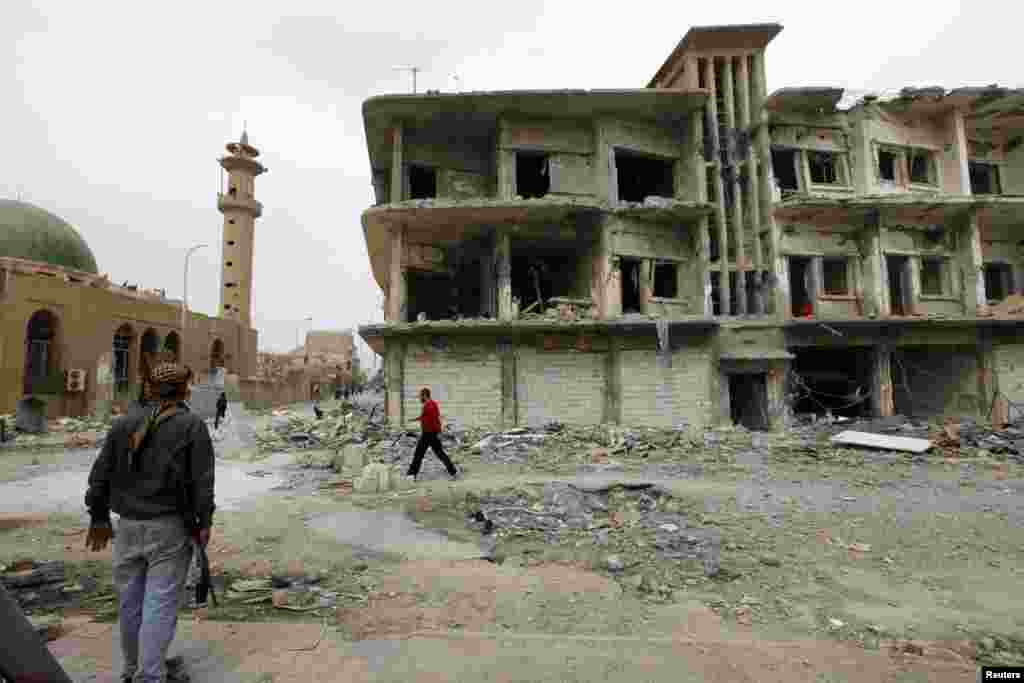 A member of the Free Syrian Army stands near a damaged building in Raqqa province, eastern Syria, March 13, 2013.