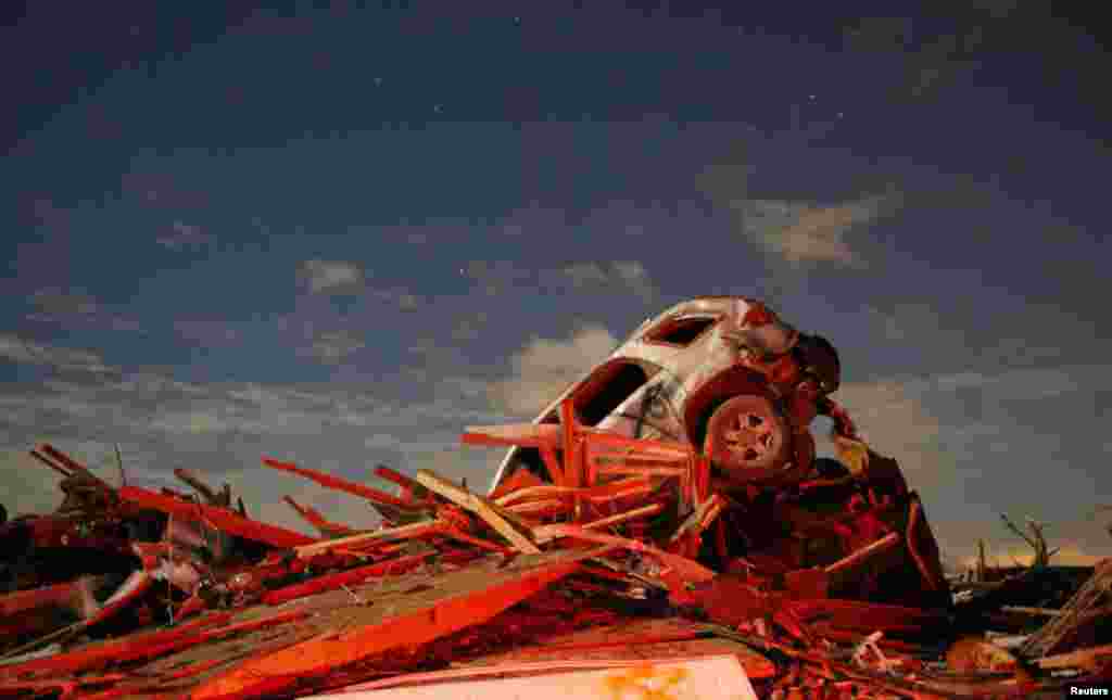 Sebuah mobil berada di atas tumpukan puing-puing akibat tornado yang mendarat di kota Washington, negara bagian Illinois, AS (17/11). 