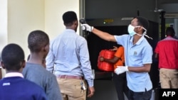 Un travailleur vérifie la température des voyageurs au poste frontière avec le Kenya à Namanga, dans le nord de la Tanzanie, le 16 mars 2020.