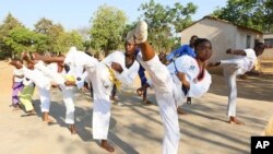 Natsiraishe Maritsa, second right, goes through taekwondo kicking drills during a practice session with young boys and girls in the Epworth settlement about 15 km southeast of the capital Harare, Saturday Nov. 7, 2020.
