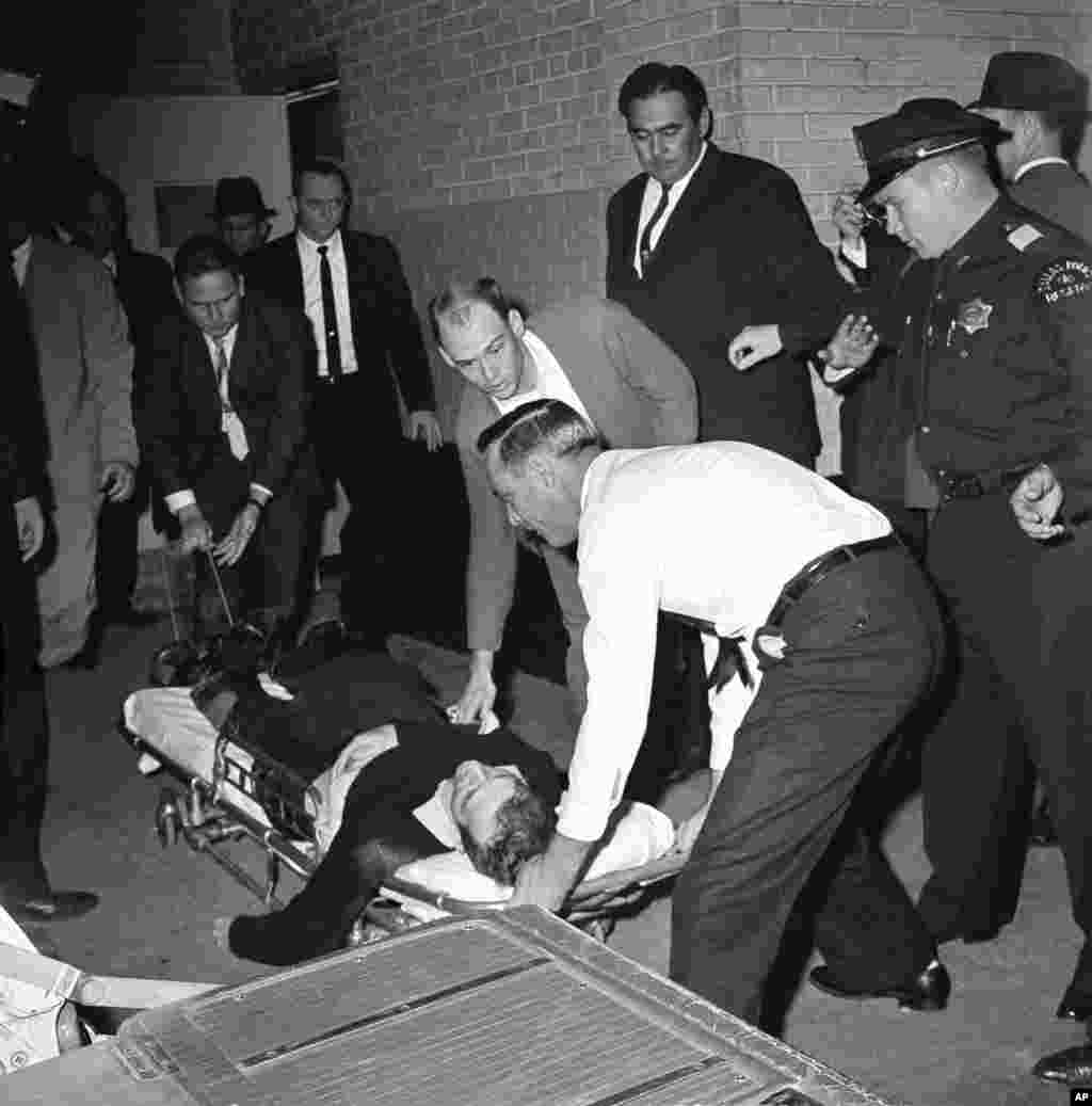 Lee Harvey Oswald, tertuduh pembunuh Presiden John F. Kennedy, diletakkan di atas tandu setelah ditembak di perut di Dallas, Texas, 24 November 1963. (AP/David F. Smith)