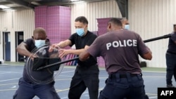 FILE - Anggota Tim Penghubung Polisi China (tengah) melatih petugas RSIPF lokal dalam latihan keterampilan tempur tanpa senjata, dalam foto yang dirilis 29 Maret 2022. (Handout / RSIPF / AFP)