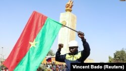Un homme tient un drapeau du Burkina Faso lors d'un rassemblement de souteien au coup d'État qui a renversé le président Roch Kaboré, Ouagadougou le 25 janvier 2022. REUTERS/Vincent Bado