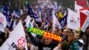 A protester holds a scarf with the word 'teacher' as tens of thousands march down Lisbon's Liberdade Avenue during a demonstration by teachers in Lisbon, Feb. 11, 2023. 
