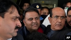 Petugas polisi berpakaian preman mengawal Fawad Chaudhry (tengah), pemimpin senior partai mantan Perdana Menteri Imran Khan, setelah pemeriksaan medial di sebuah rumah sakit di Lahore, Pakistan, 25 Januari 2023.