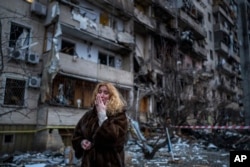 Reaksi Natali Sevriukova di samping rumahnya menyusul serangan roket di kota Kyiv, Ukraina, Jumat, 25 Februari 2022. (Foto: AP/Emilio Morenatti)