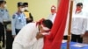 Satu dari delapan narapidana terorisme di Sumut sedang mencium bendera Merah Putih, Rabu 9 Maret 2022. (Courtesy: Humas Kemenkumham Sumut).