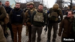 Ukraine's President Volodymyr Zelenskiy looks on as he stands with Ukrainian servicemen, amid Russia's invasion of Ukraine, in Bucha, outside Kyiv, Apr. 4, 2022.