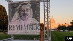 Penulis Turki Hatice Cengiz (kanan), tunangan jurnalis Saudi dan pembangkang Jamal Khashoggi, berpose di sebelah potret Khashoggi setelah dipamerkan di National Mall di Washington, DC., pada 1 Oktober 2021. (Foto: AFP)
