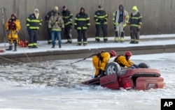 Regu penyelamat dari satuan pemadam kebakaran kota Kansas berupaya mengangkat mobil minivan yang terpelosok ke Sungai Brush di Kansas City, Missouri, 22 Desember 2022. (Nick Wagner/The Kansas City Star via AP)