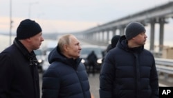 El presidente ruso, Vladimir Putin, en el centro, y el viceprimer ministro Marat Khusnullin, a la izquierda, visitan el puente de Crimea que conecta la parte continental de Rusia y la península de Crimea sobre el estrecho de Kerch, que resultó dañado por un atentado con camión bomba en octubre, después de las obras de restauración, no lejos de Kerch , Crimea, lunes 5 de diciembre de 2022.