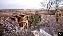 Menteri Pertahanan Rusia Sergei Shoigu, tengah, berjalan keluar dari parit, dikawal oleh sekelompok perwira saat dia memeriksa pasukan Rusia di lokasi yang dirahasiakan di Ukraina, 22 Desember 2022. (Foto: via AP)