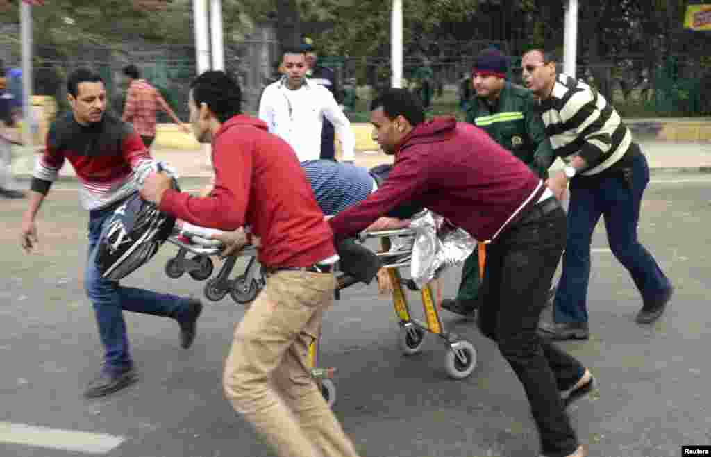 People use a stretcher to transport the body of a police officer who was killed in explosions near Cairo University, April 2, 2014.
