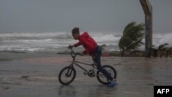 ARCHIVO - Un joven monta su bicicleta en la playa de Nagua, República Dominicana, el 19 de septiembre de 2022, cuando el huracán Fiona pasa por el país.