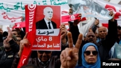FILE - People carry banners and flags during a rally in support of Tunisian President Kais Saied in Tunis, Tunisia, May 8, 2022.