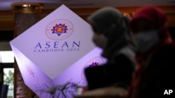 Dua perempuan bermasker berjalan di depan logo ASEAN di sebuah hotel tempat Pertemuan Menteri Luar Negeri ASEAN ke-55 (AMM ke-55) berlangsung di Phnom Penh, Kamboja, Selasa, 2 Agustus 2022. (Foto: AP)