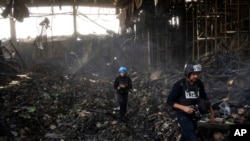 Wartawan berjalan di dalam gudang yang hancur untuk menyimpan makanan, setelah serangan dari Rusia di Brovary, di pinggiran Kyiv, Ukraina, 29 Maret 2022. (Foto: AP)
