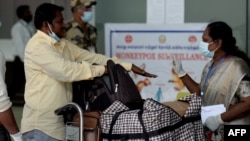 Petugas kesehatan tampak memeriksa penumpang yang tiba dari luar negeri untuk mengetahui apakah penumpang tersebut memiliki gejala terinfeksi cacar monyet. Pemeriksaan itu dilakukan di Bandara Internasional Anna di Chennai, India, pada 3 Juni 2022. (Foto: AFP/Arun Sankar)