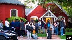 Immigrants gather with their belongings outside St. Andrews Episcopal Church, Sept. 14, 2022, in Edgartown, Mass., on Martha's Vineyard. 