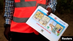 Un agent de santé ougandais montre un dépliant d'information sur le virus Ebola et comment empêcher sa propagation à la communauté du village de Kirembo, près de la frontière avec la RDC, dans le district de Kasese, en Ouganda, le 15 juin 2019.