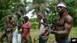 Des combattants Ijaw, armés de fusils AK-47, montent la garde à Okorota, près de Port Harcourt, au Nigéria, le 25 juin 2014.