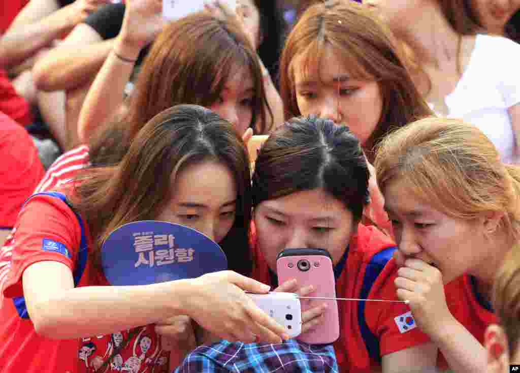 Gadis-gadis Korea Selatan melihat tim Korsel bertanding melawan Rusia dari ponsel pintar mereka karena 'layar lebar' untuk nonton bersama (nobar) mati akibat kerusakan teknis di Seoul.