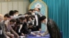 Pemimpin Tertinggi Iran Ayatollah Ali Khamenei disambut oleh pekerja pemilihan, semuanya mengenakan masker wajah karena pandemi COVID-19, saat ia tiba untuk memberikan suaranya pada 18 Juni 2021. (Foto: AFP)