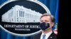 FBI Director Christopher Wray listens during a virtual news conference at the Department of Justice, October 28, 2020, in Washington. The Justice Department has charged eight people with working on behalf of the Chinese government.