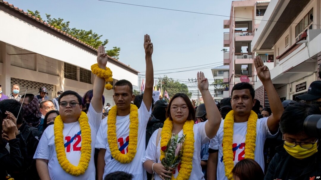 Pro-democracy movement protest leaders from left, Parit Chiwarak, Panupong Jadnok, Panusaya Sithijirawattanakul and Shinawat Chankrajang flash three-finger salute as they walk to appear in a police station in Northaburi, Thailand, Tuesday, Dec. 8, 2020. Four leaders report to ack