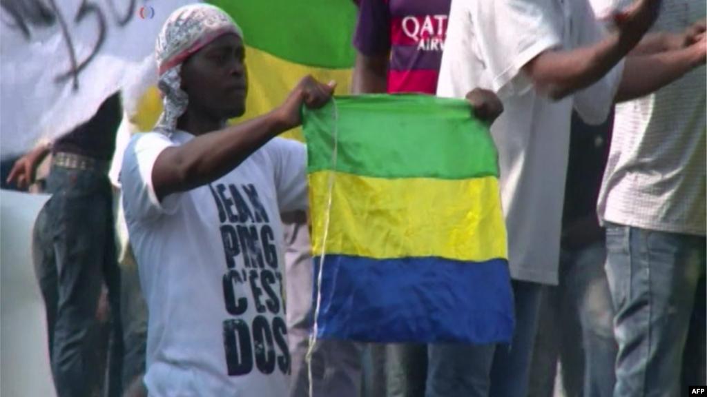 Un manifestant brandit le drapeau du Gabon lors des émeutes qui ont éclaté après l'annonce officielle de la réélection du président sortant du Gabon, Ali Bongo Ondimba à Libreville, le 30 août 2016.