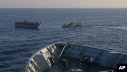 In this photo released by the Italian Navy on April 9, 2014, Italian Navy's dingies approach a boat carrying migrants along the Mediterranean sea, off the Sicilian island of Lampedusa