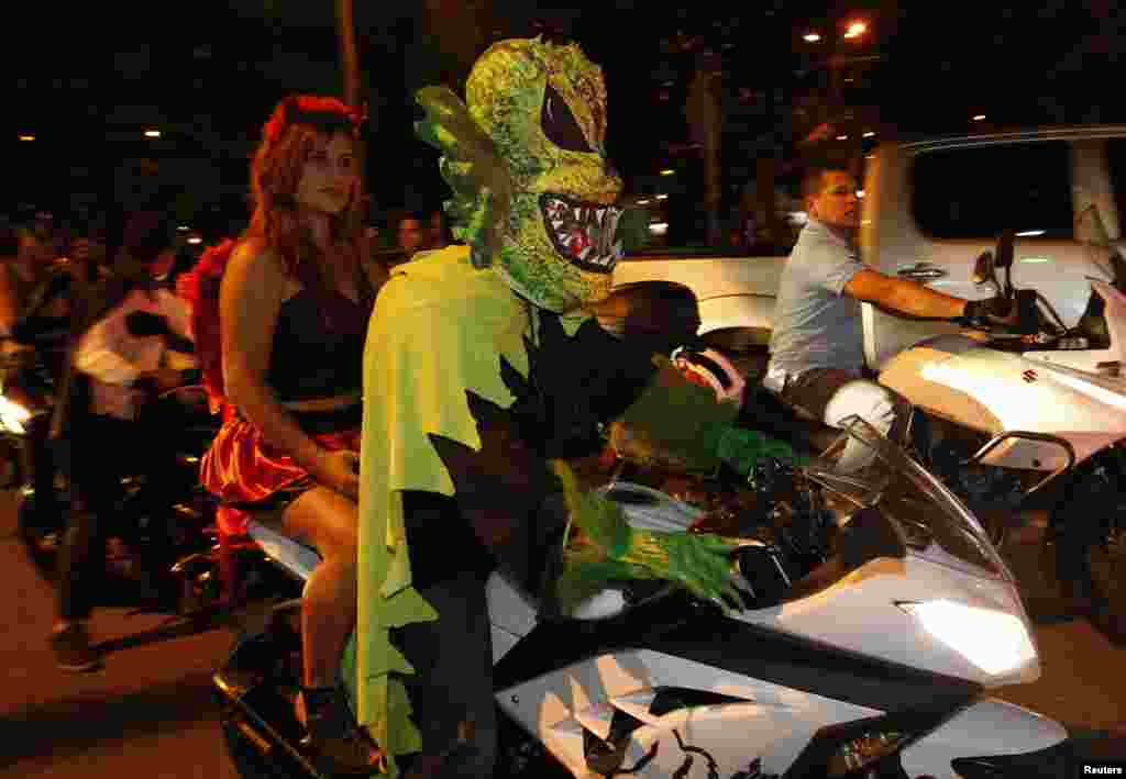 A couple dressed in costumes ride a motorbike during the "Moto Halloween Party 2013" in Cali, Colombia, Oct. 30, 2013.