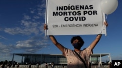 Seorang demonstran membawa poster bertuliskan suku asli Indian di Brazil yang banyak menjadi korban COVID-19. 