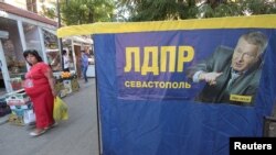 Seorang wanita berjalan melewati sebuah poster kampanye pemilihan Vladimir Zhirinovsky, pemimpin partai Rusia Liberal Demokrat, menjelang pemilihan parlemen 18 September di pelabuhan Laut Hitam dari Sevastopol, Krimea, 16 September 2016. (REUTERS/Pavel Rebrov).
