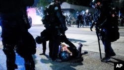Police officers detain a protester outside the Portland Police Association building, in Portland, Oregon, Sept. 4, 2020.