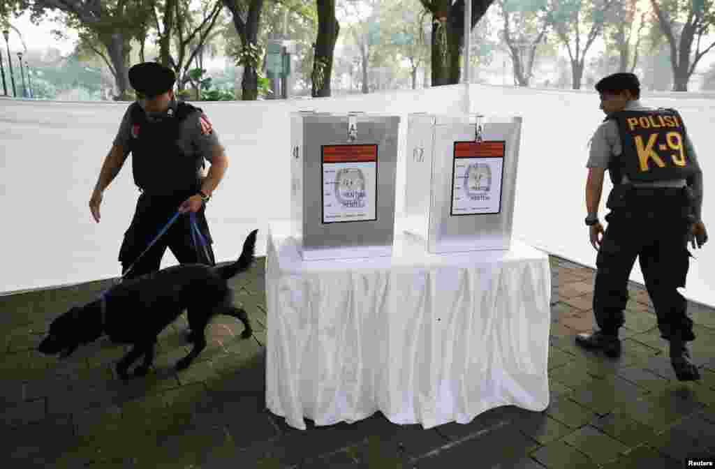 Polisi menggunakan anjing pelacak memeriksa TPS Taman Surapati, tempat kandidat presiden Joko "Jokowi" Widodo dan istrinya Iriana akan memilih (9/7). (Reuters/Darren Whiteside)