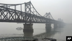 Truk-truk melintas jembatan yang menghubungkan Korea Utara dengan Kota Dandong di perbatasan China, 3 Maret 2016. 