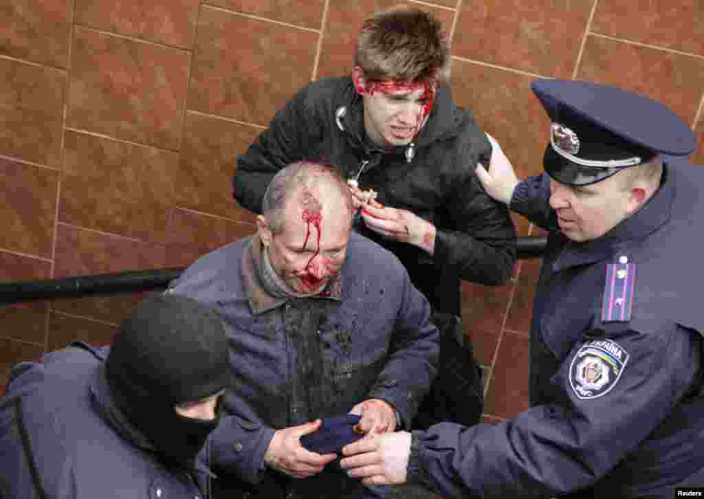 Interior Ministry members stand near men who were injured in clashes between pro-Russian and pro-Ukrainian supporters during rallies, in Kharkiv, Ukraine, April 13, 2014. 