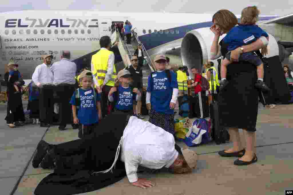 A newly-arrived Jewish immigrant coming from North America with his family kisses the tarmac upon their arrival at the Ben Gurion International Airport near Tel Aviv in Israel.