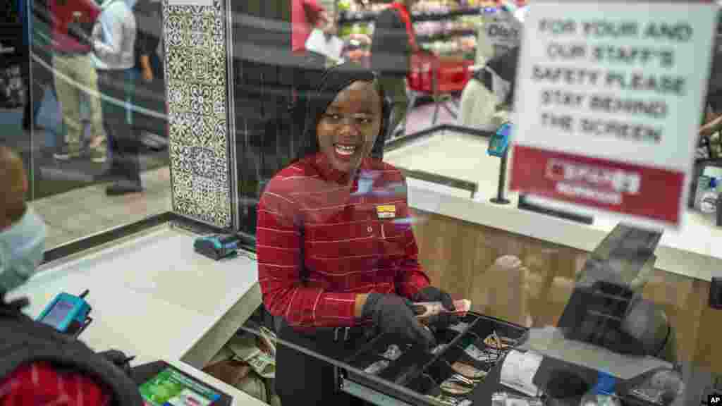 La empleada de un supermercado en un suburbio de Johannesburgo, Zandile Mlotshwa, de 21 años, cuenta el dinero colectado en su caja al final de su turno. Alrededor del mundo, empleados de supermercados y otros negocios esenciales permanecen en primera línea para ofrecer productos de primera necesidad como alimentos.