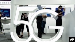 Pengunjung yang mengenakan masker untuk melindungi dari virus corona berjalan melewati tanda 5G di China Beijing International High Tech Expo di Beijing, China pada Kamis, 17 September 2020. (Foto: AP/Ng Han Guan)