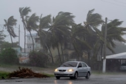 Un automóvil circula en una carretera cuando la tormenta tropical Laura azota Guayama, Puerto Rico, el 22 de agosto de 2020.