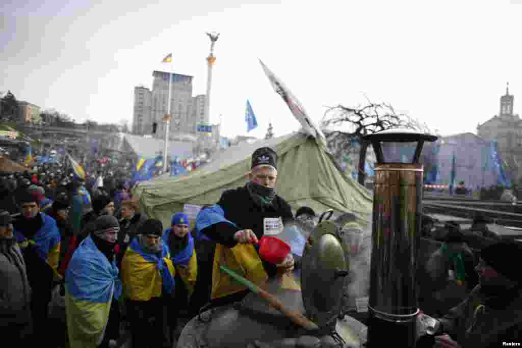A man wrapped in a Ukrainian flag distributes tea to protesters at Independence Square in Kyiv, Dec. 4, 2013.