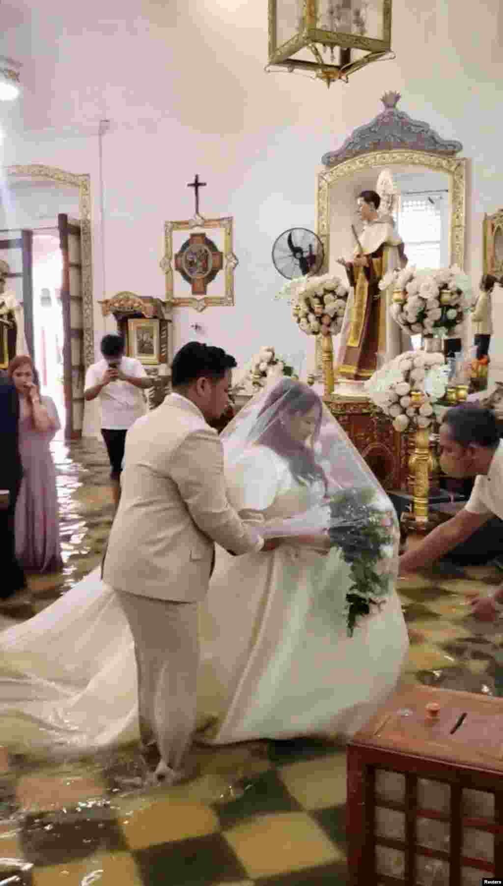 Bibi harusi atolewa kanisani mjini Malolos, Ufilipino baada ya mafuriko kutokea mafuriko ndani ya kanisa kufuatia kimbunga Doksuri. 