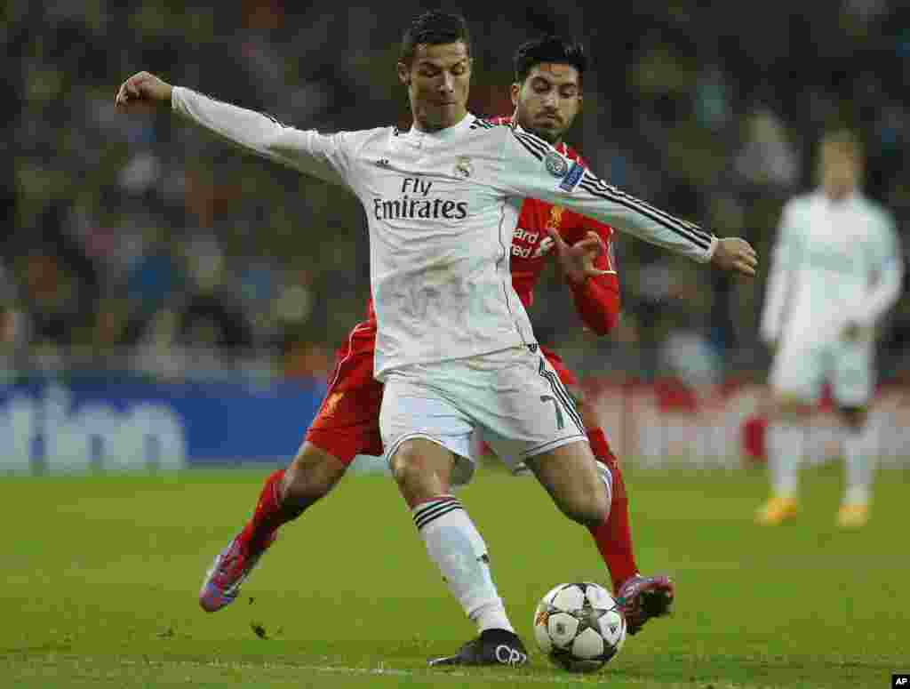 Cristiano Ronaldo du Real Madrid, devant, se lance avec le ballon dans une avec Emre Can de Liverpool lors d'un match de football, Groupe B, de la Ligue des Champions entre le Real Madrid et Liverpool au stade Santiago Bernabeu à Madrid, Espagne, le mardi 4 novembre 2014.