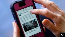 FILE - A mobile phone is used to access news from The Huffington Post on Facebook, in Los Angeles, April 28, 2015.