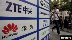 一名中国男子从武汉街头有着华为和中兴标徽的广告牌前走过。（资料照片）