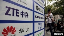 一名中國男子從武漢街頭有著華為和中興標徽的廣告牌前走過。 （資料照片）