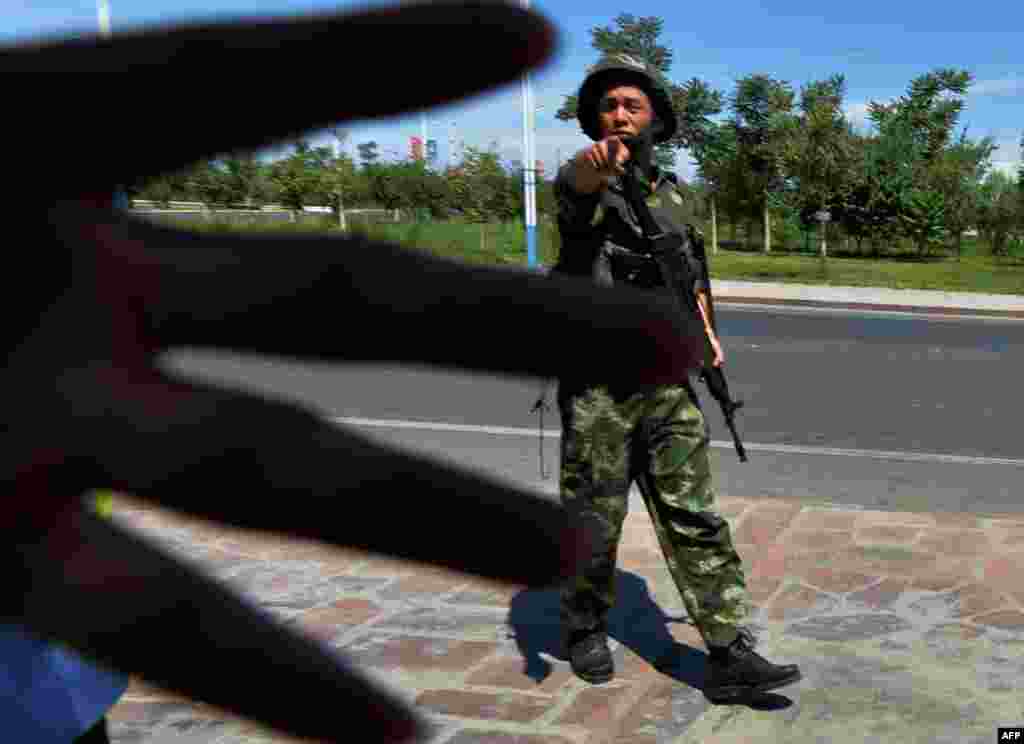 Seorang polisi militer China memblokir pengambilan foto ketika seseorang melewati sebuah pos pemeriksaan menuju Kota Lukqun, Uighur, yang sedang dilanda kerusuhan di Provinsi Xinjiang. Kekerasan baru meletus di provinsi yang bergolak tersebut, dua hari setelah 35 orang tewas dalam apa yang disebut pemerintah sebagai 'serangan teroris' dan seminggu sebelum terjadinya peringatan 3 tahun bentrokan besar pada tahun 2009.