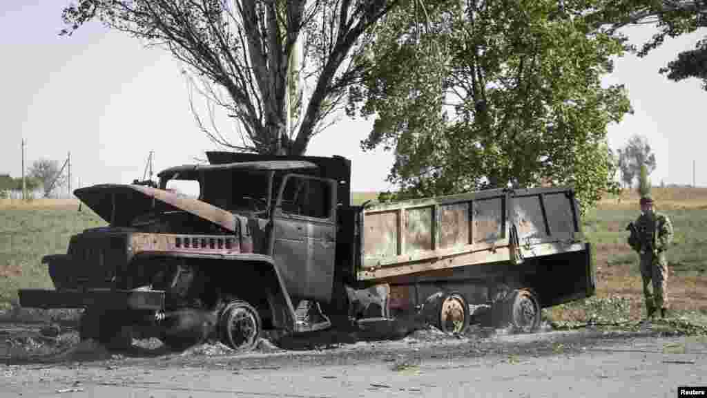 A Ukrainian soldier looks at a truck burned by recent shelling on the outskirts of the southern coastal town of Mariupol, Ukraine, Sept. 7, 2014.